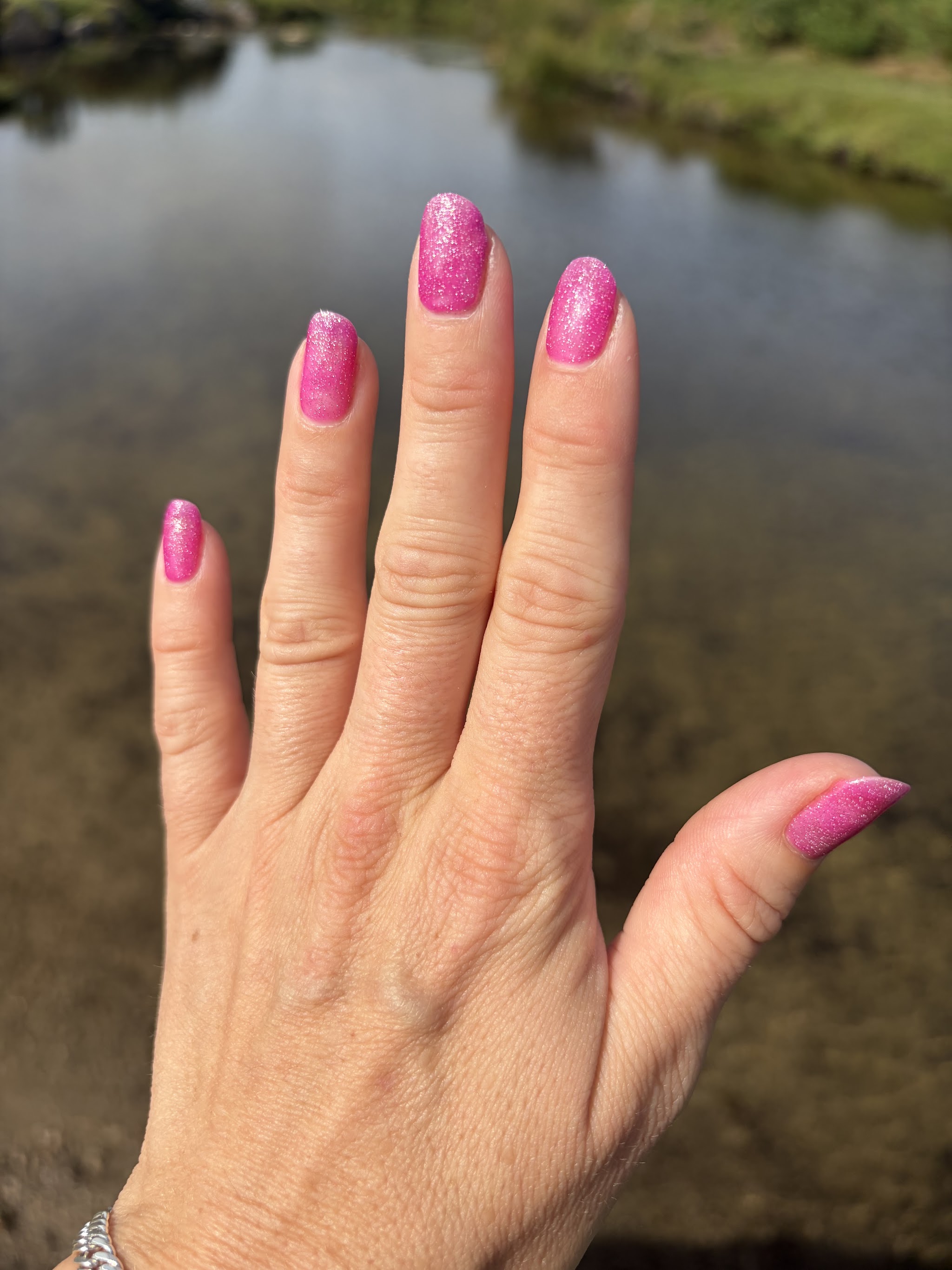 A customer showing off her glitter pink nails outdoors